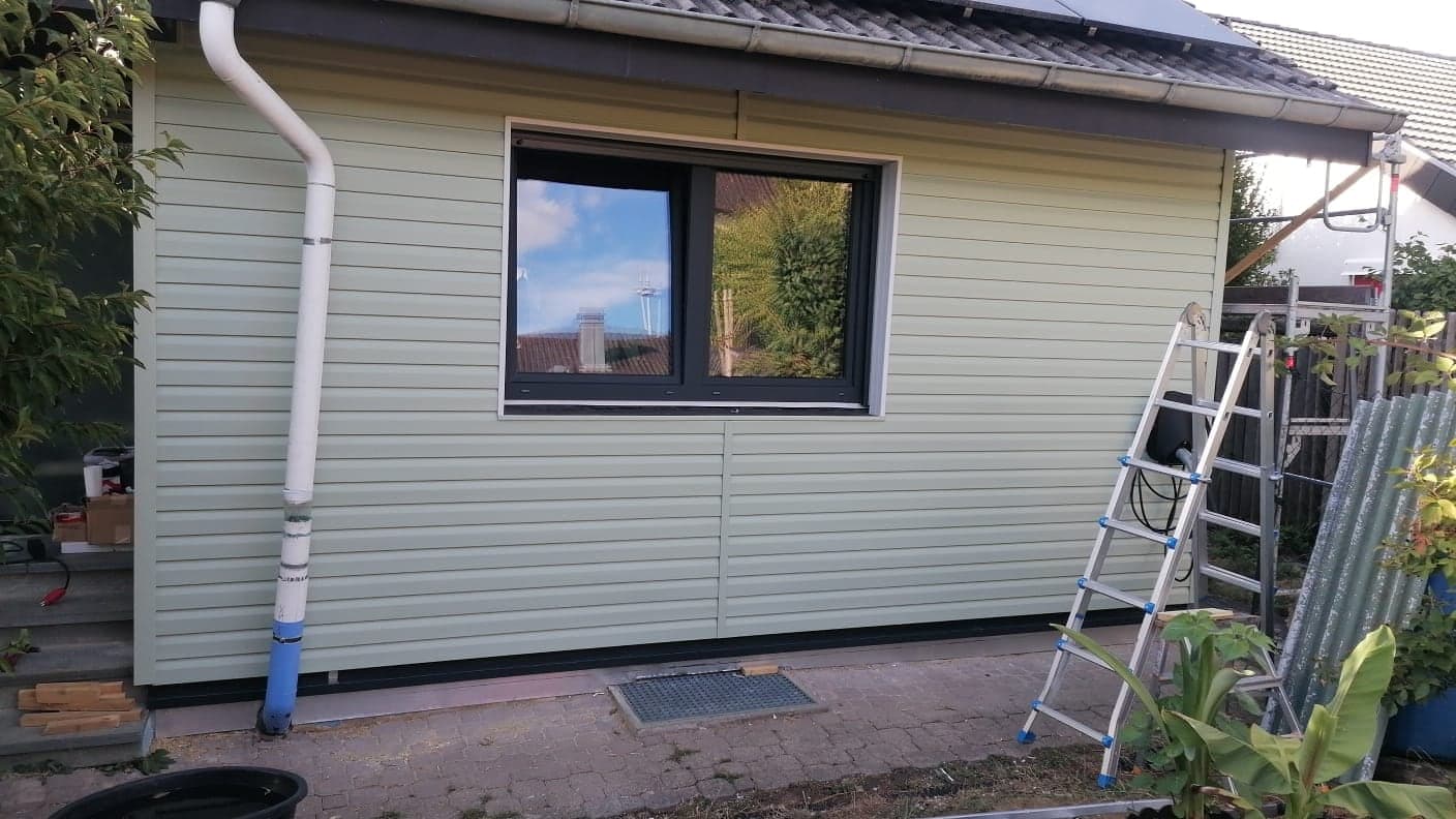 Zweiteiliges Anthrazit-Fenster in der fertigen Giebelwand mit hellgrüner Verkleidung